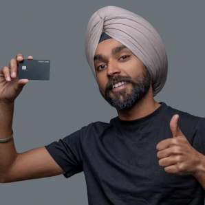 Person wearing a turban and a black shirt, holding a premium credit card and giving a thumbs up.