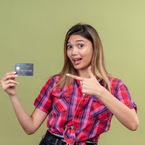 Individual wearing a plaid shirt, pointing to a credit card, highlighting the best reward credit card.